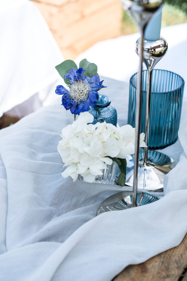 Tisch-Dekoration mit blau-weißen Blumen und Kerzenständer